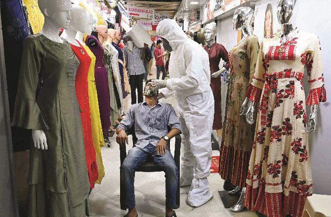 An employee of the clothing wholesale market is checking the health worker code.Pictrue: PTI