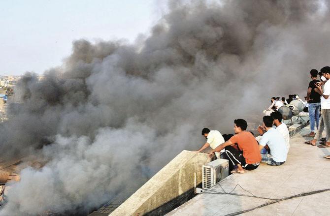 Smoke rising from the warehouse Some people are watching from the top of a building in the distance..Picture:Inquilab,Sameer Abidi