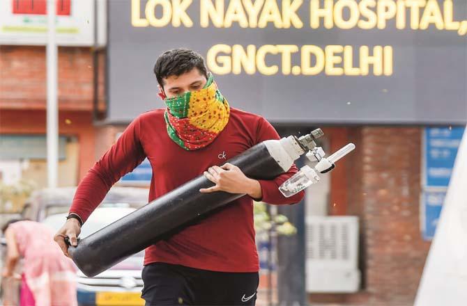 A man carries an oxygen cylinder for a relative undergoing treatment at the LNJP Hospital in Delhi.Picture:PTI