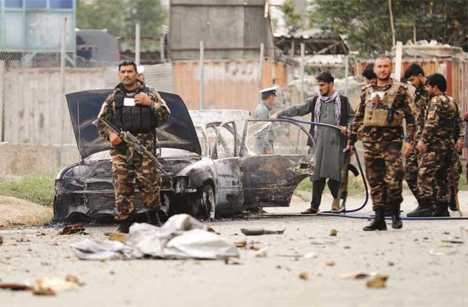 Security personnel inspect a car destroyed in the attack.  Ashraf Ghani.Picture:PTI