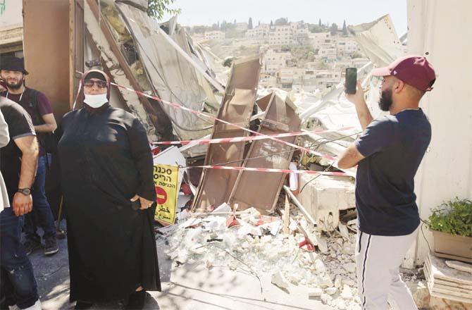 A Palestinian woman near her collapsed house (Agency)