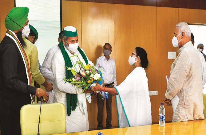 Chief Minister Mamata Banerjee taking a bouquet from farmer leader Rakesh Tikit during the meeting. Picture: PTI