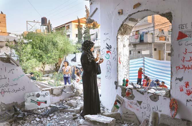 A female artist performs on the wall of a destroyed building in Gaza (Photo: Agency)