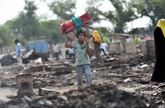 A boy stands between the ashes of Rohingya refugees. (Picture:PTI)