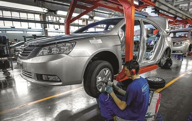 An employee in a car factory can be seen installing tires in the structure of a new car.Picture:INN