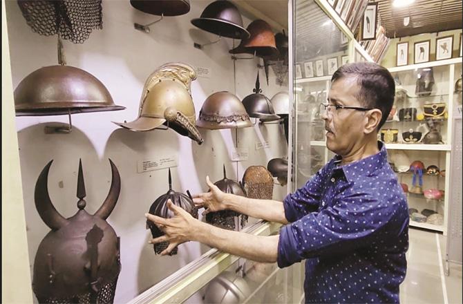Anant Joshi showing off the war hats in his museum.