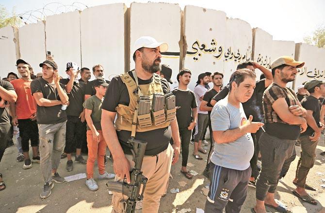 A security guard can be seen among protesters in Baghdad.Picture:Agency