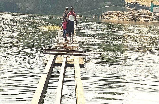 A man and a woman pass by this dangerous bridge of Alhas river.