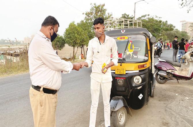 A policeman collects a fine from a rickshaw driver in vasai.