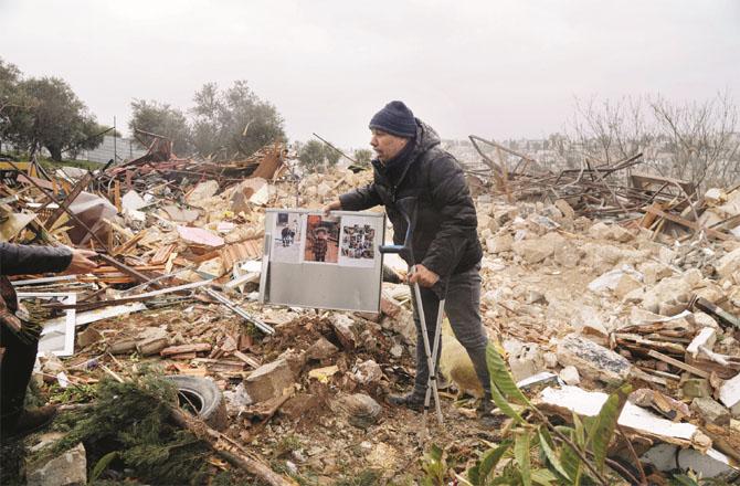 Local social worker Muhammad Abu Al-Hamous collects family photos and essential items from the rubble of a collapsed house. (PTI)