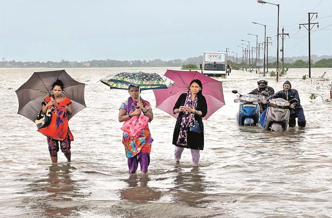 Pedestrians and motorists can be seen passing under the flooded road in vasai Sun City.
