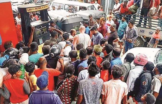 Queue and wait: People stand for fuel at a petrol pump in Colombo..Picture:INN