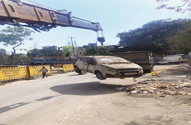 A policeman removes a car parked on the road with the help of a crane.