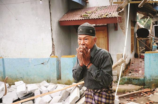 A man stands a picture of helplessness near his destroyed house in Sianjur. Picture:AP/PTI