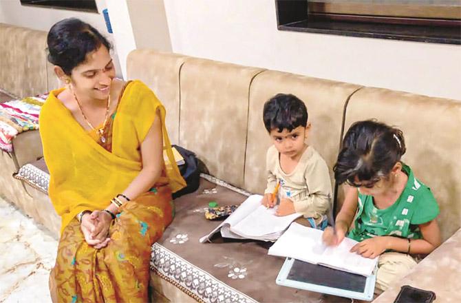 After the evening siren, a mother looks happy to see her children reading and writing. (PTI)