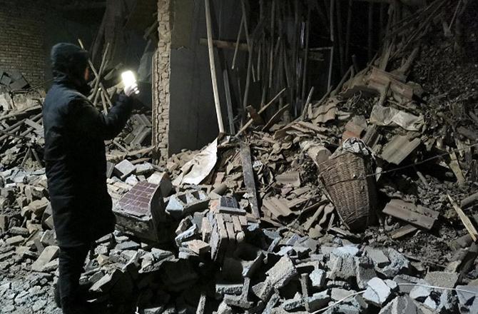 A government employee inspecting a destroyed house after the earthquake. Photo: PTI