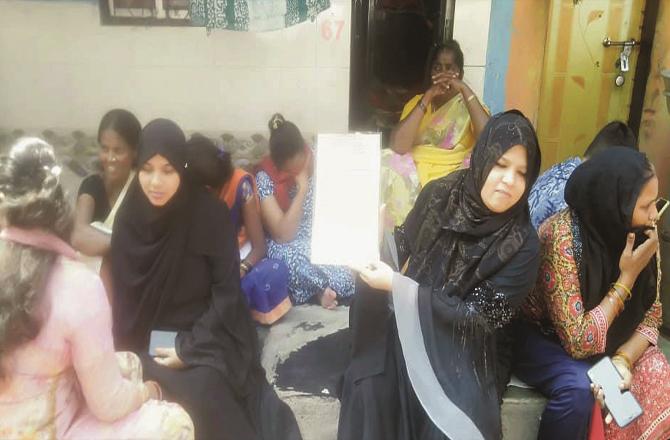 A woman shows the notice while other women look worried about the demolition notice.