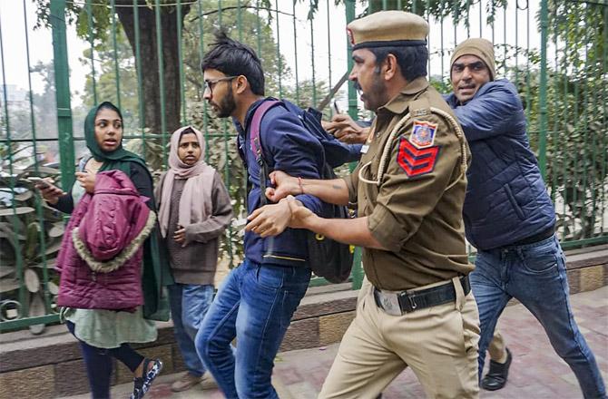 Police officers detaining a student from the campus of Jamia Millia Islamia. (PTI)