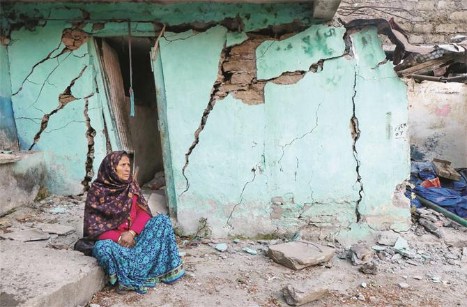A woman of Joshi Mutt is worried outside her broken house; (Photo: PTI)
