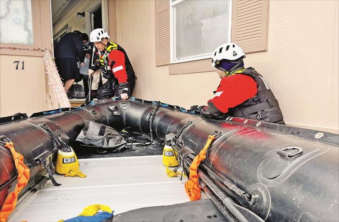 Rescuers attempt to enter a flooded house.