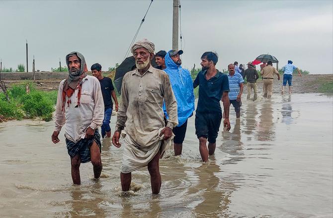 People are moving to safer places after the water level of river Chenab rises. Photo: PTI