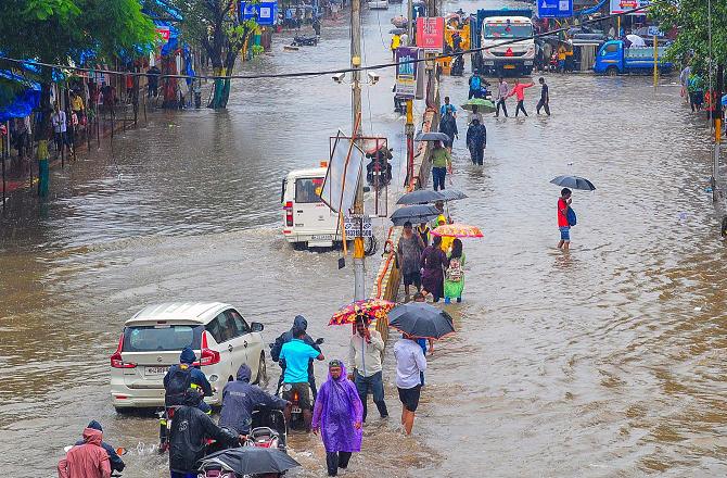 Commuters on a waterlogged road during monsoon rainfall, at Nalasopara in Palghar districtPhoto : PTI