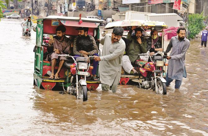 Rickshaw drivers are passing through the flooded road. (AP/PTI)