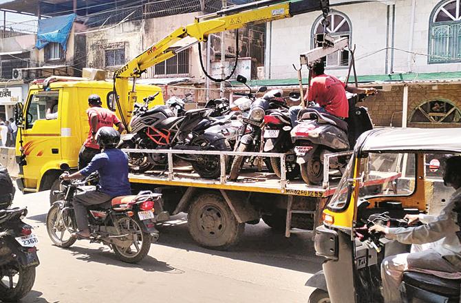 In Malwani , the traffic police officers were picking up the two-wheelers parked on the side of the road.