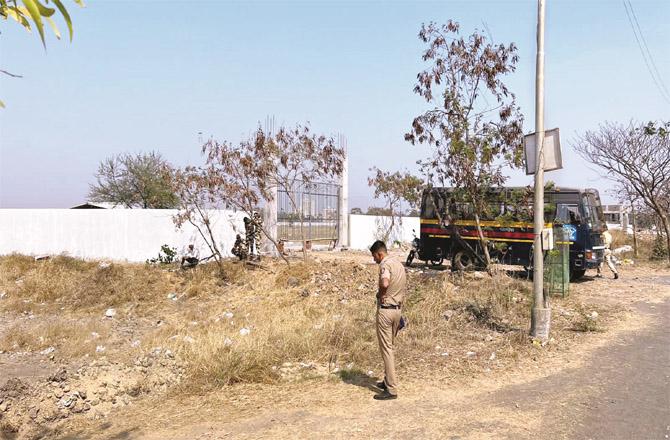A police guard is seen outside Sun City Cemetery in Vasai.