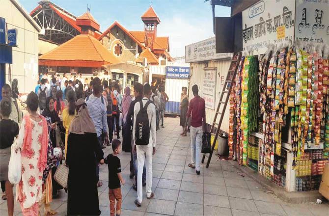 Passengers queue outside the ticket window set up in a container outside Bandra station