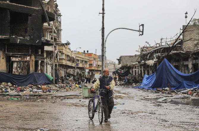 A Palestinian walks down a damaged road in Gaza. Photo: PTI