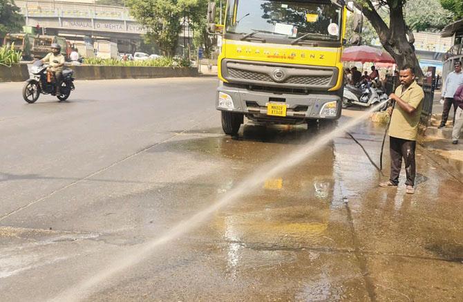 A municipal employee can be seen washing a city road with water. Photo: INN