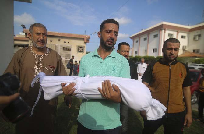 A child killed in an Israeli attack in Gaza is carried by his father. Photo: PTI