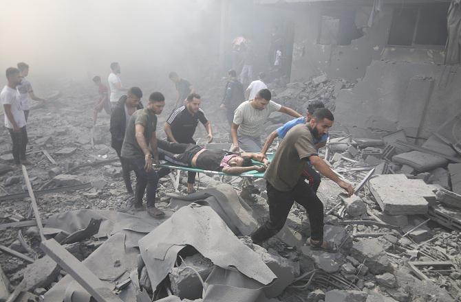 Palestinians pulling an injured youth from the rubble. Photo: PTI