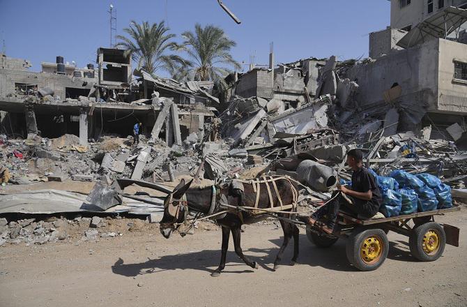 A Palestinian walks through the rubble of destroyed buildings. Photo: PTI