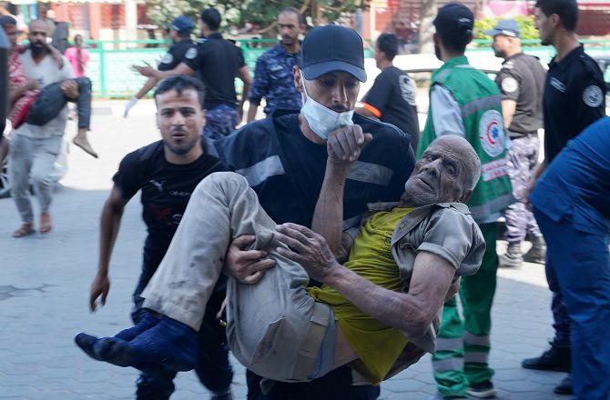 Palestinian youth carrying an elderly Palestinian victim to the hospital. Photo: PTI