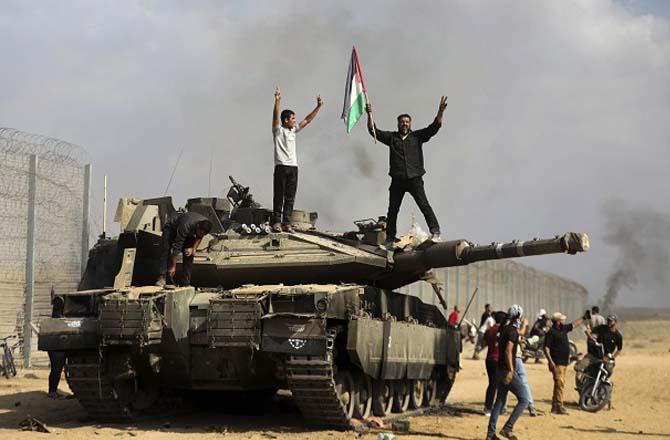 Palestinian fighters celebrate after destroying an Israeli tank. Photo: PTI