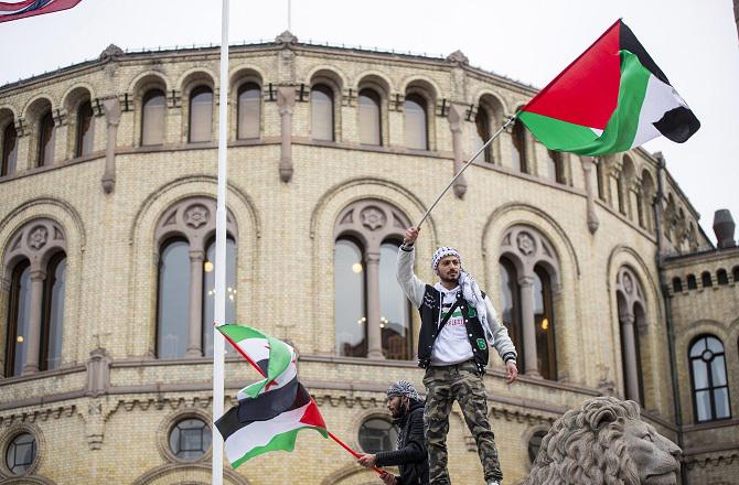 A man waves a Palestinian flag in front of the parliament in Oslo, Norway. Photo: PTI