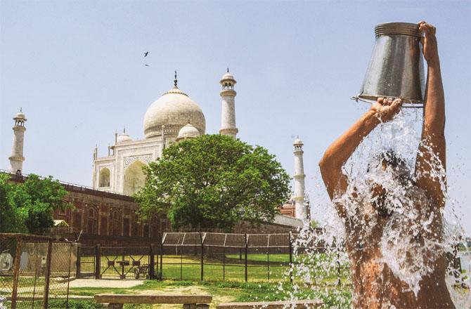 A man takes a bucket bath to escape the heat in Agra. (PTI)