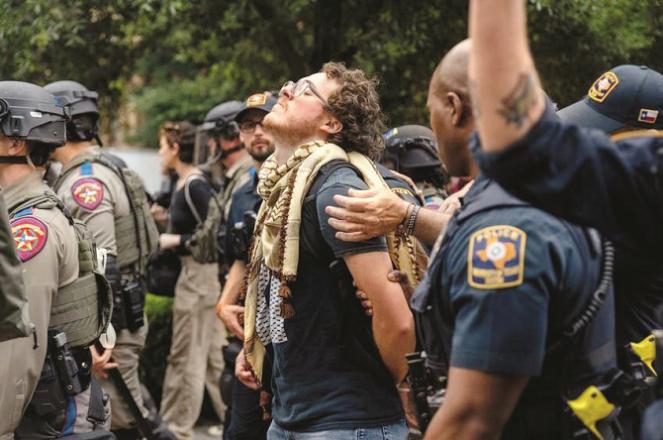 Police escort a student to a van after arresting him at the University of Texas. Photo: INN