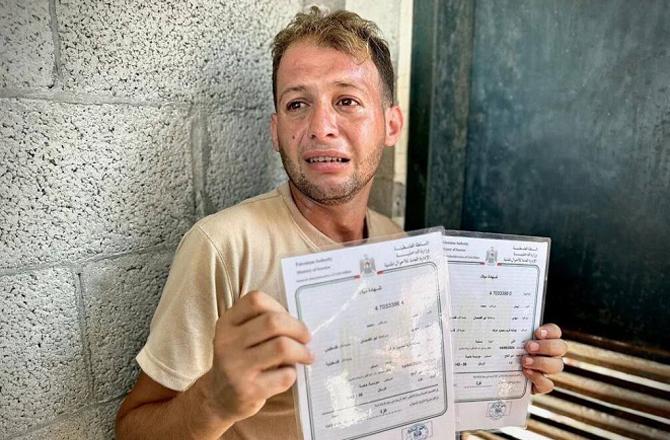 The father of the martyred twins cries while showing their birth certificate. Photo: X.