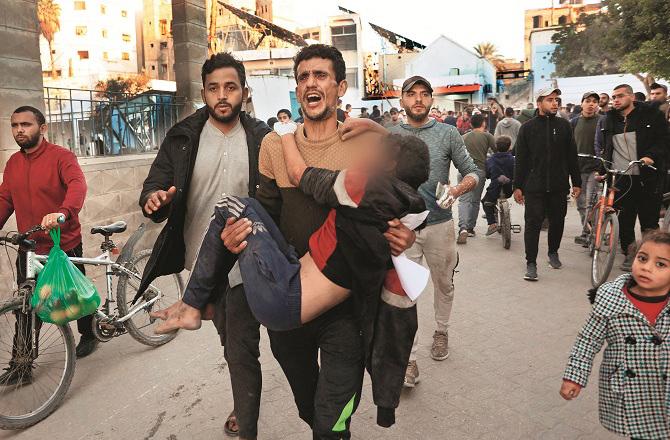 A child injured in an Israeli attack is being taken to the hospital by his father. Photo: INN