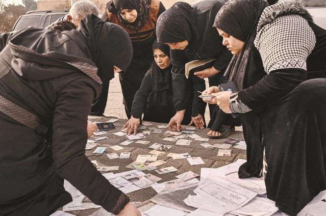 Women at al-Muzha Military Airport, looking through prison documents to trace their relatives. Photo: INN