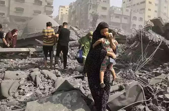 People walk through the rubble of a building after an Israeli attack. Photo: PTI