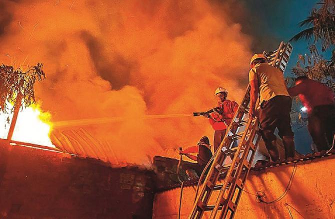 Fire brigade personnel can be seen putting out the fire. Photo: PTI