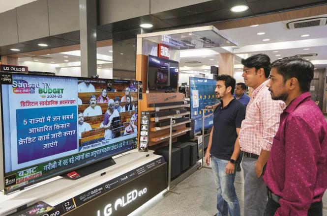 People watch Union Budget presented by Nirmala Sitharaman on TV in a noisy room in Lucknow. Photo: PTI