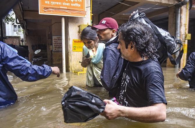 Officials evacuate people to safer places after a community is flooded. Photo: PTI