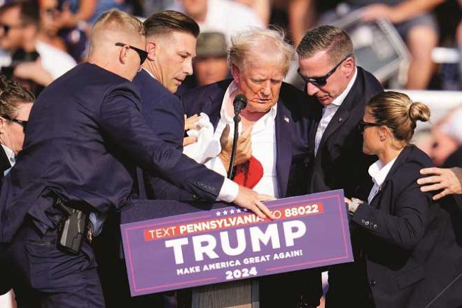 Secret Service agents carrying Trump off the stage after he was injured in the attack. Photo: Agency
