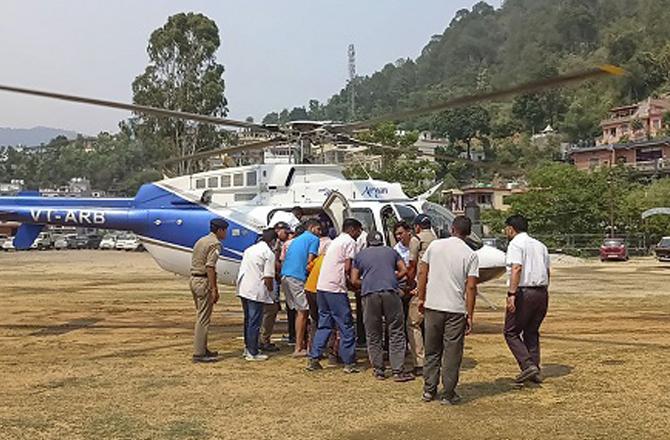 Rescue officials bringing the injured to Rudraprayag by helicopter. Photo: PTI