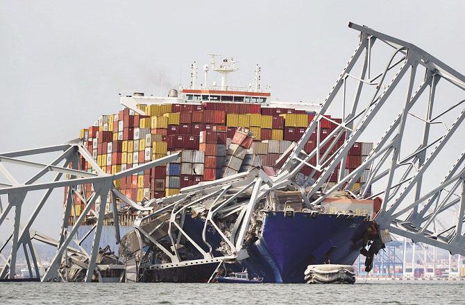 The wreckage of the collapsed bridge can be seen above the cargo ship Dilly. Photo: PTI